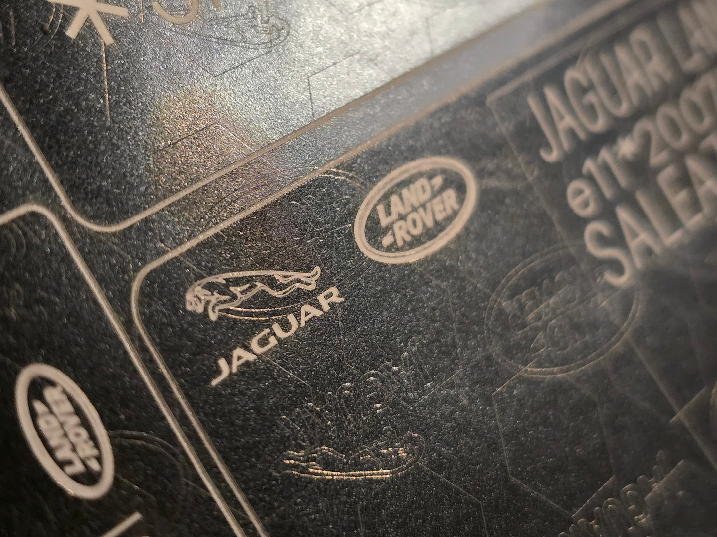 Close-up of black VIN shield plate with Jaguar and Land Rover logos for vin stickers, vin plates, chassis plates, vin tags, data plates, anti tamper vin labels