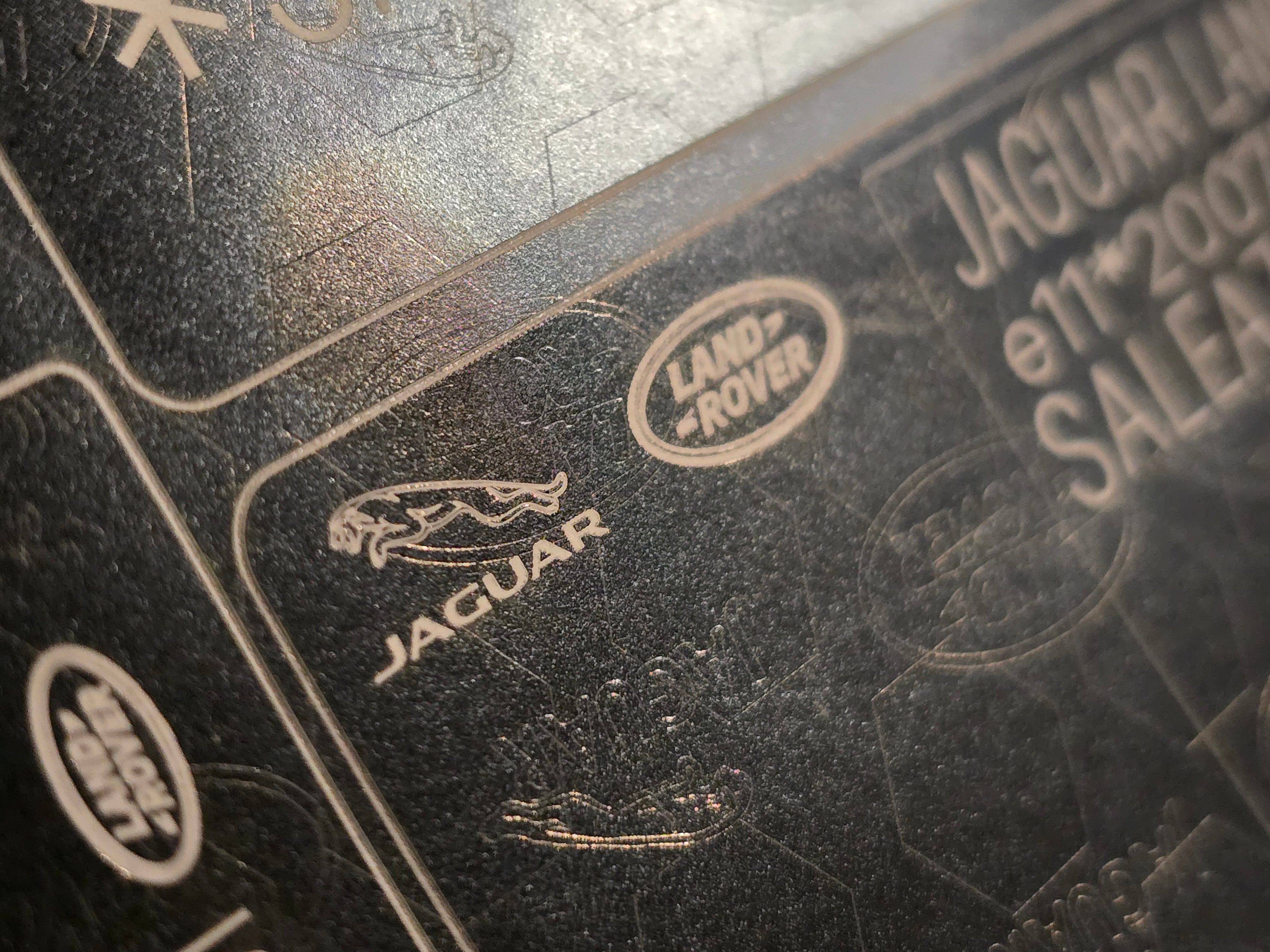 Close-up of black VIN shield plate with Jaguar and Land Rover logos for vin stickers, vin plates, chassis plates, vin tags, data plates, anti tamper vin labels