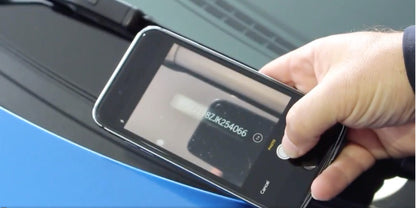 Hand using smartphone to scan VIN number on car windshield featuring vin stickers vin plates chassis plates vin tags data tags data plates