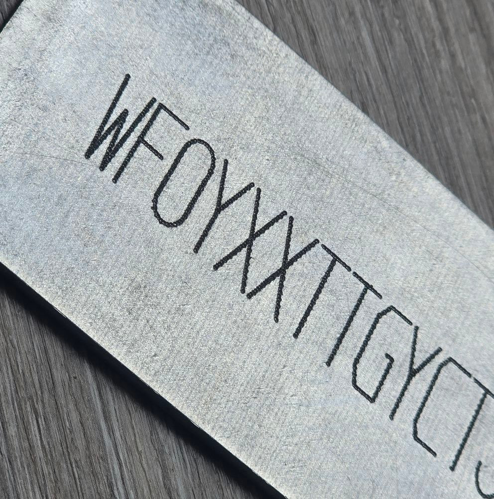 Close-up of a BMW replacement VIN sticker decal plate showing a serial number on textured surface